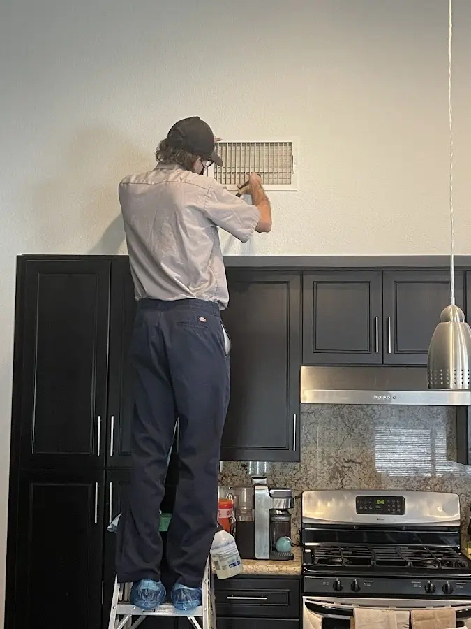 Technician inspecting an air vent during HVAC service in Plainfield